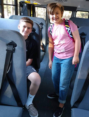 Two Chevelon Butte students posing together on a bus