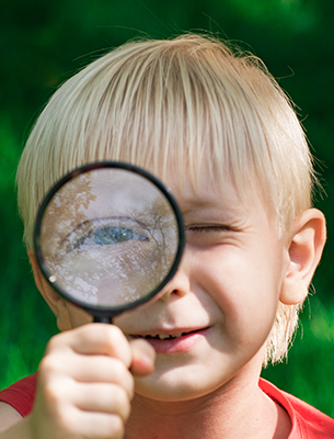 Boy holding a magnifying glass up to his eye